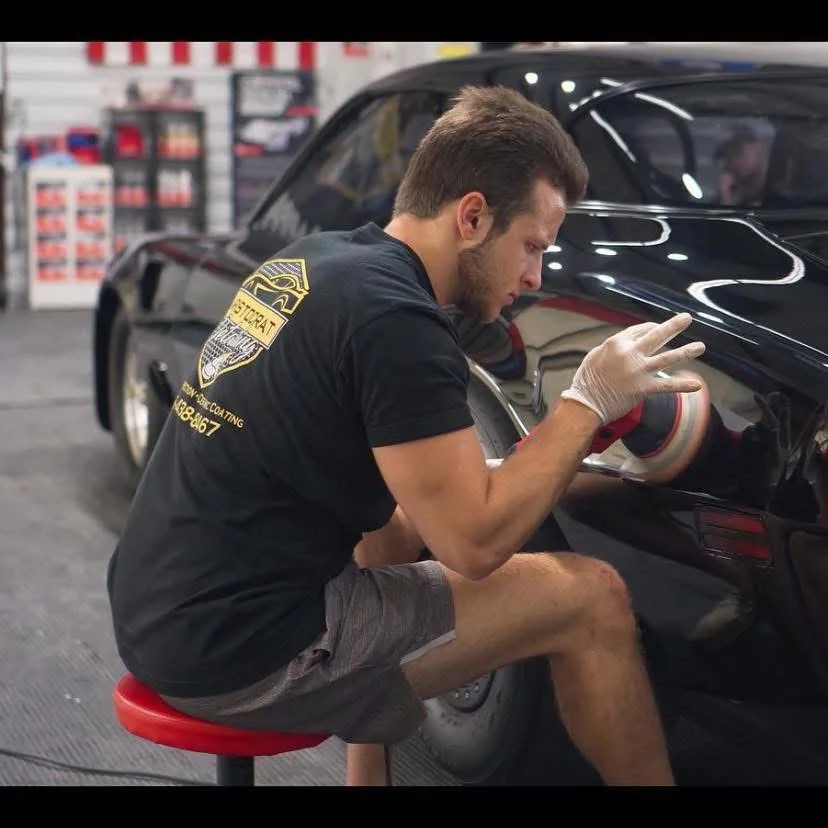 Aristocrat Detailing technician performing paint correction on a black sports car in the Raymore shop