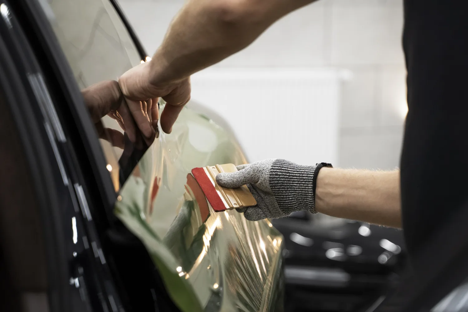 Professional window tint installation — gloved hand applying film with squeegee